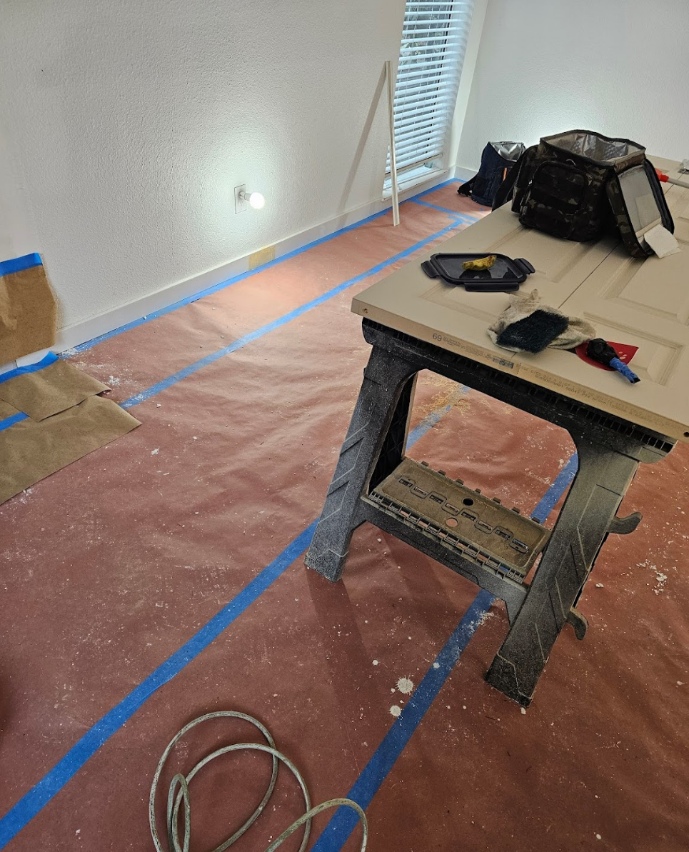 Room prepped with protective covers and tools for painting
